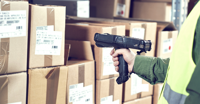 A worker pointing a wireless barcode scanner at a box label.